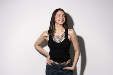 Photo of Portrait of smiling tattooed woman on light background