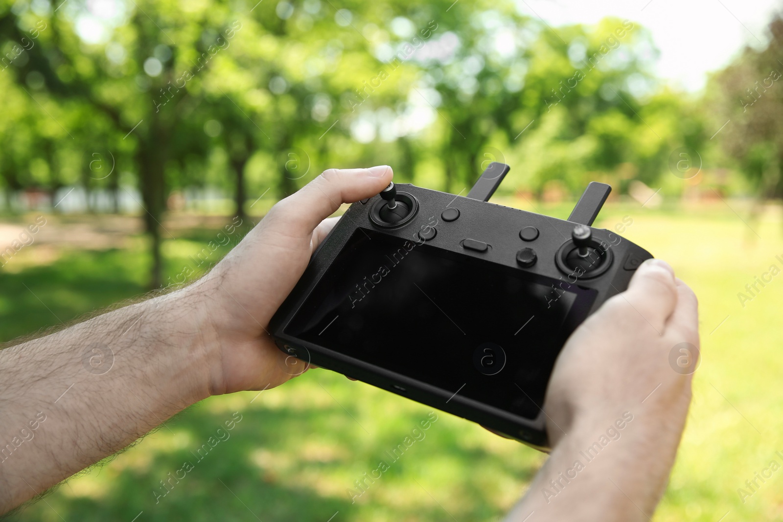 Photo of Man holding new modern drone controller outdoors, closeup of hands