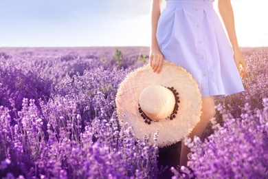 Photo of Young woman with hat in lavender field on summer day, closeup