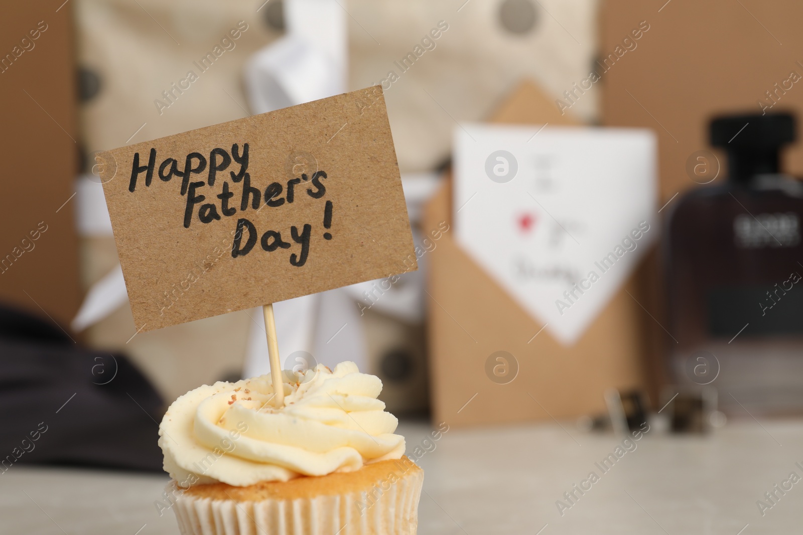 Photo of Happy Father's Day. Tasty cupcake with greetings on blurred background, closeup. Space for text