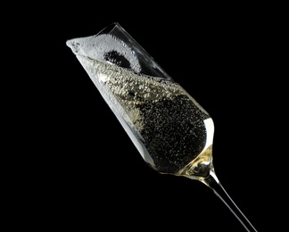 Photo of Glass of fizzy champagne on black background, closeup