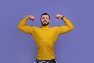 Photo of Handsome man showing muscles on purple background