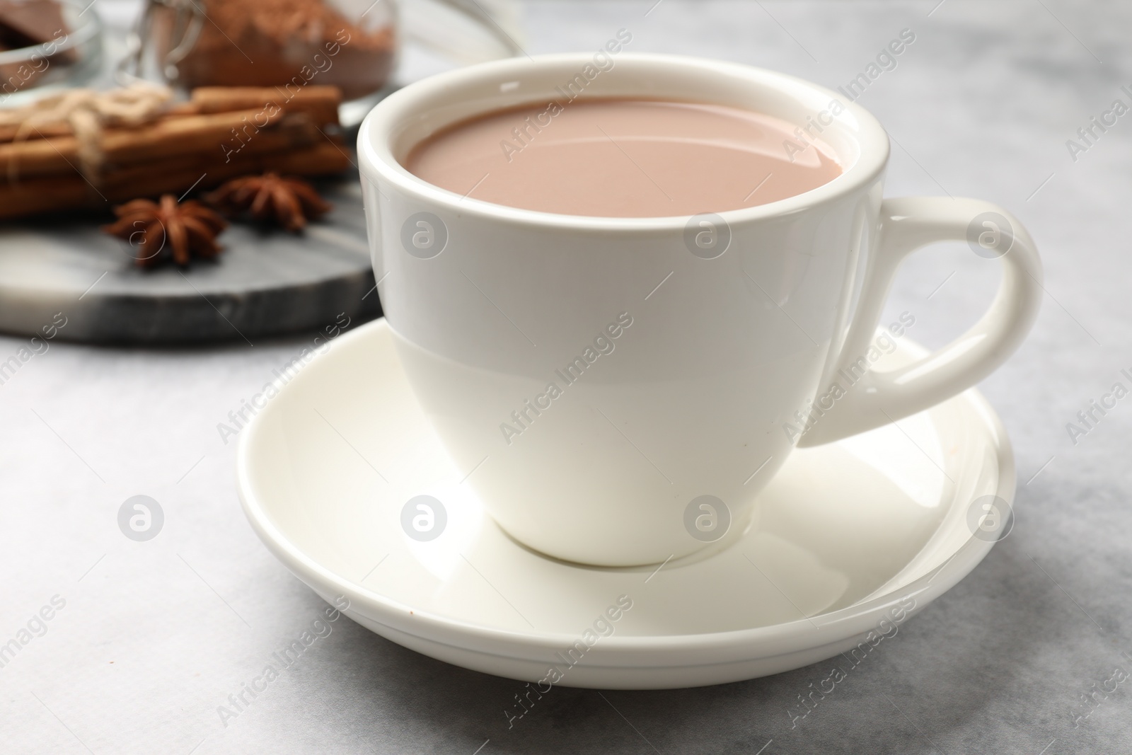 Photo of Tasty hot chocolate in cup on grey textured table, closeup