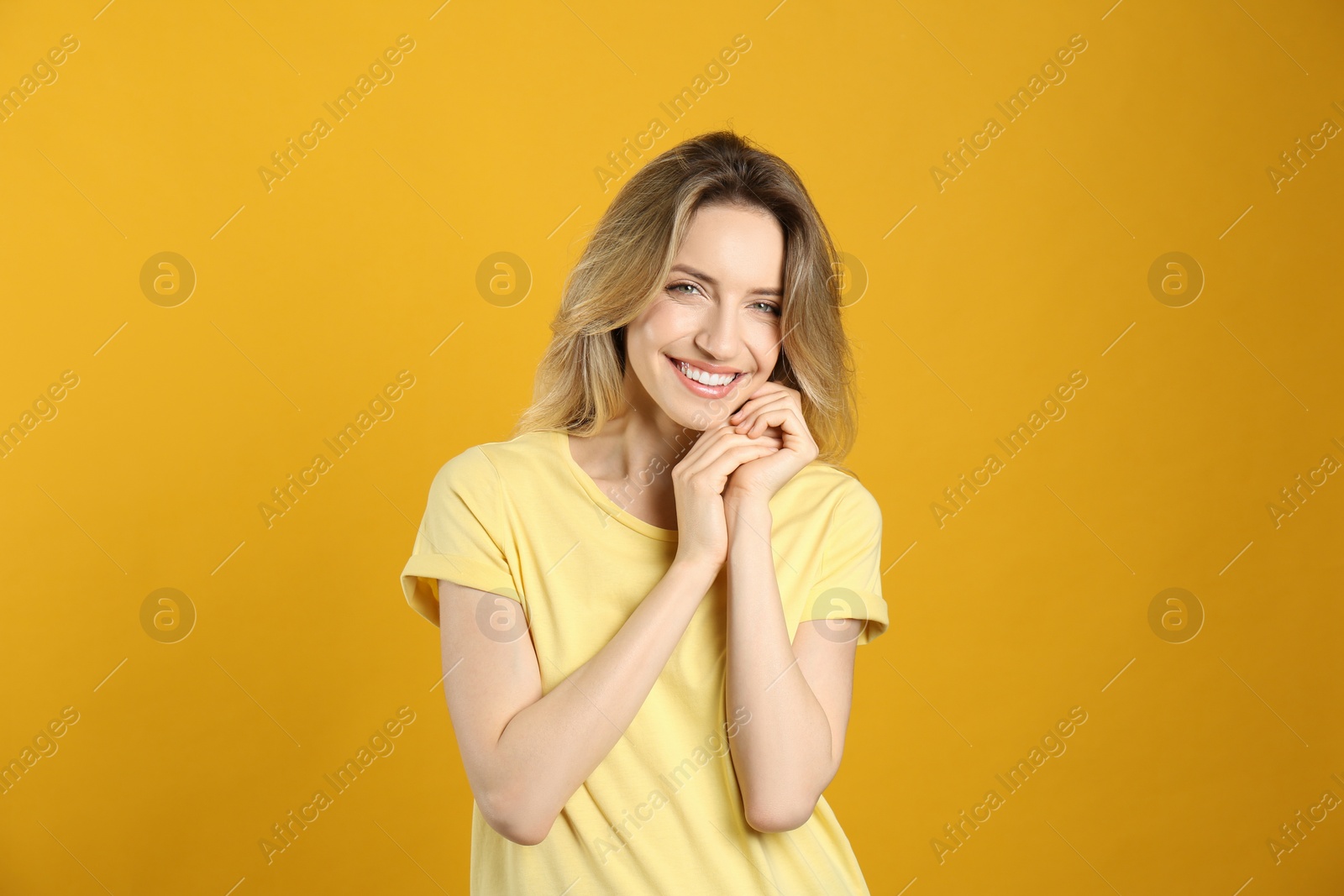 Photo of Portrait of happy young woman with beautiful blonde hair and charming smile on yellow background