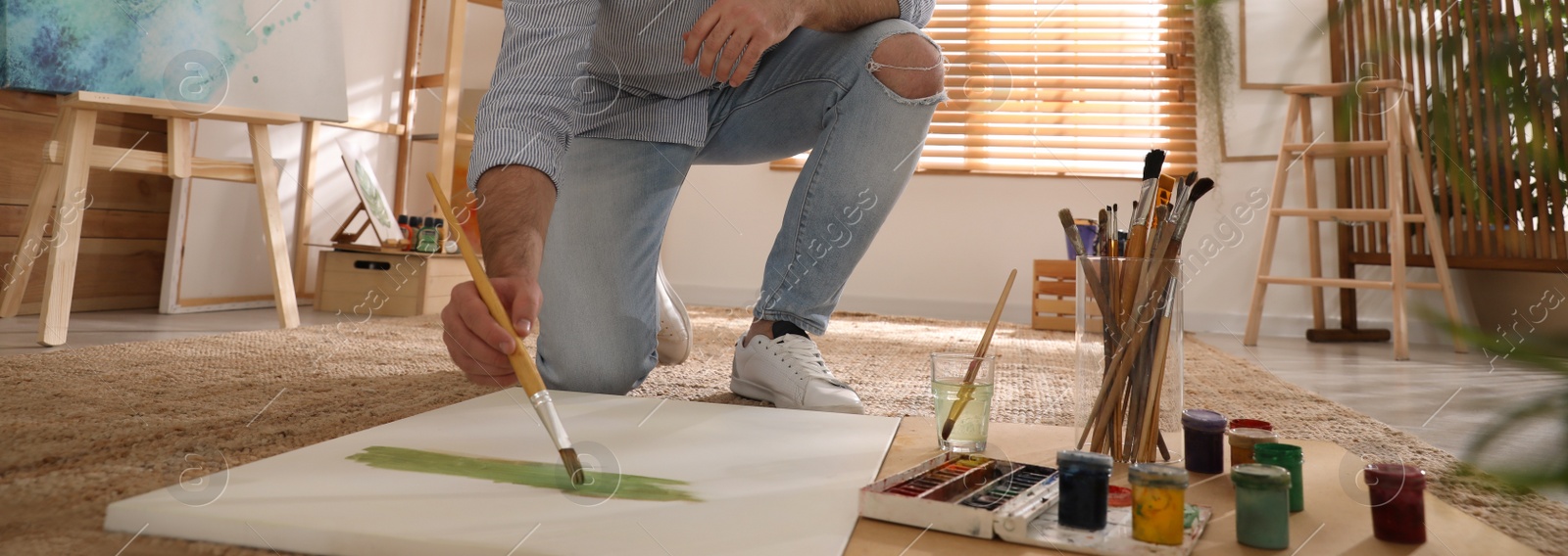 Image of Young man painting with brush in artist studio, closeup. Banner design