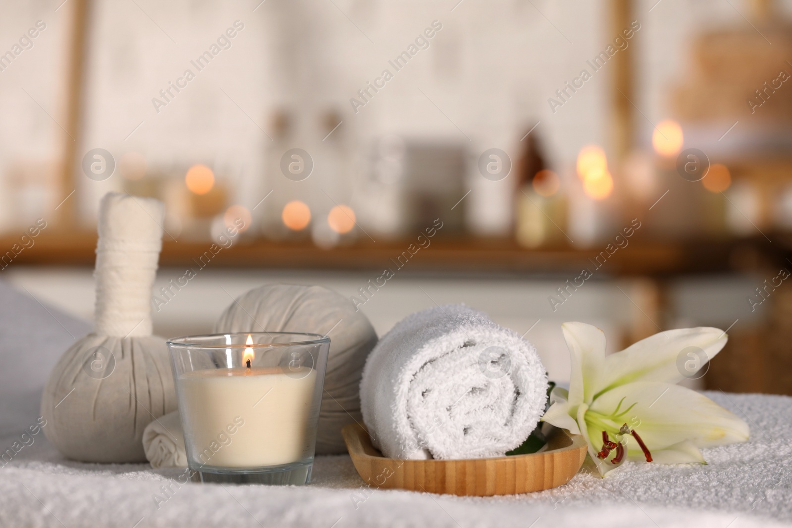 Photo of Spa composition with burning candle and herbal bags on massage table in wellness center