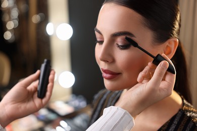 Photo of Makeup artist working with beautiful woman in dressing room, closeup