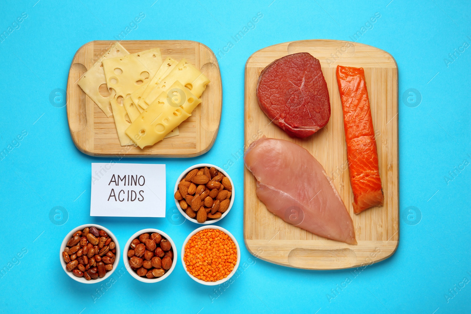 Photo of Different fresh products and paper with words Amino Acids on light blue background, flat lay