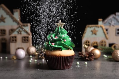 Sprinkling powdered sugar on Christmas tree shaped cupcake