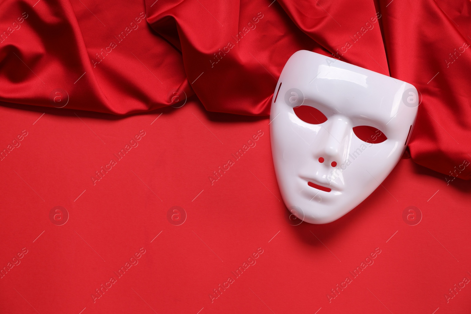 Photo of Theater arts. White mask and fabric on red background, top view. Space for text