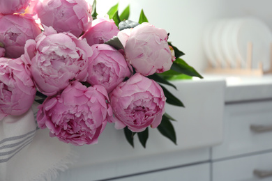 Photo of Bouquet of beautiful pink peonies on counter in kitchen, closeup