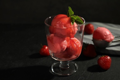 Delicious strawberry ice cream in dessert bowl on black table against dark background