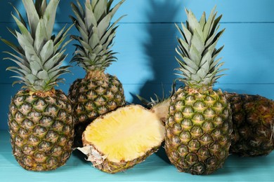 Photo of Whole and cut ripe pineapples on light blue wooden table