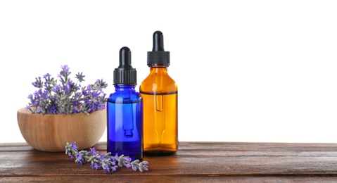 Bottles of essential oil and bowl with lavender on wooden table against white background