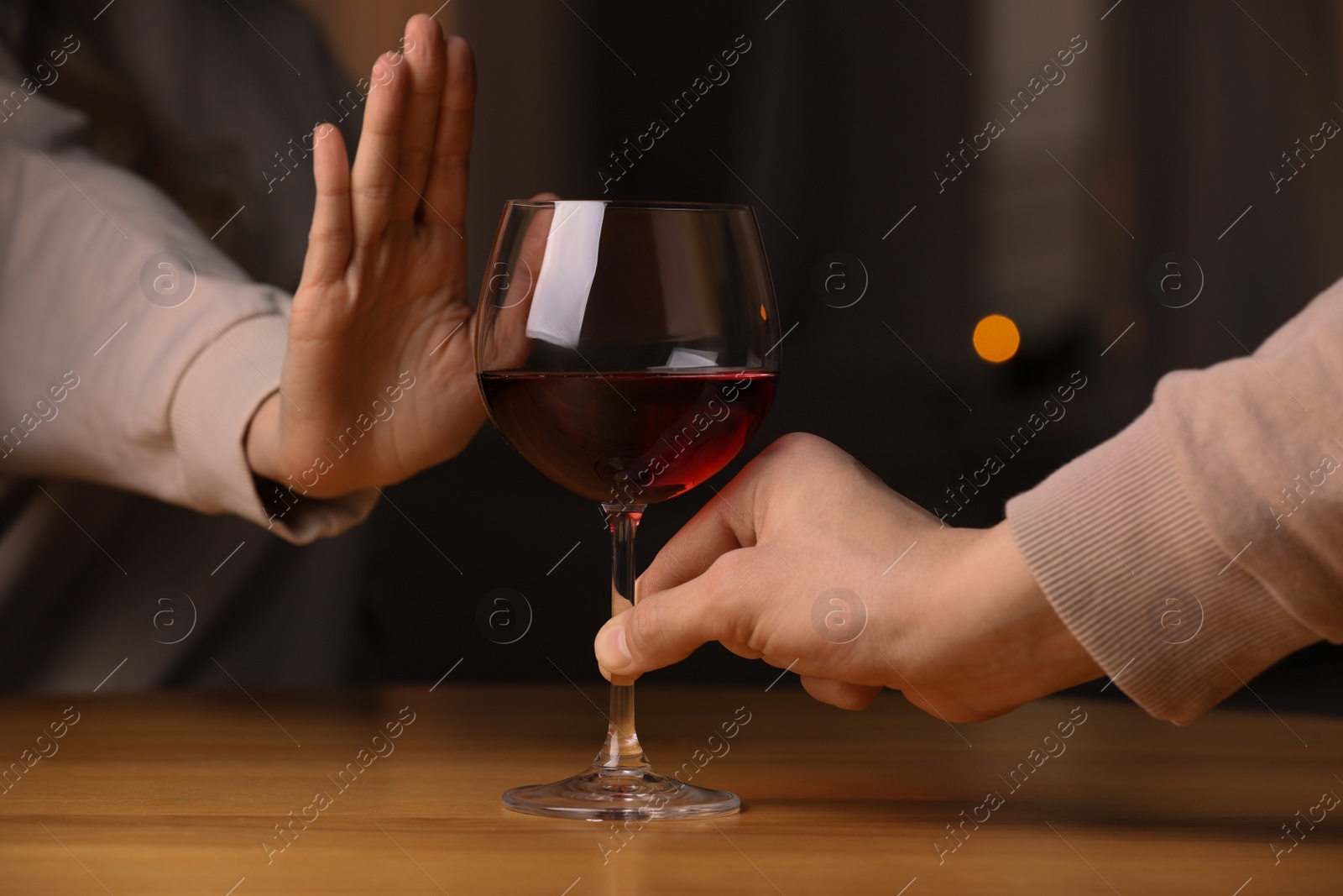 Photo of Woman refusing to drink red wine indoors, closeup. Alcohol addiction treatment