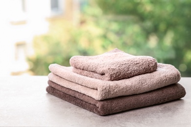 Stack of clean towels on table against blurred background. Space for text