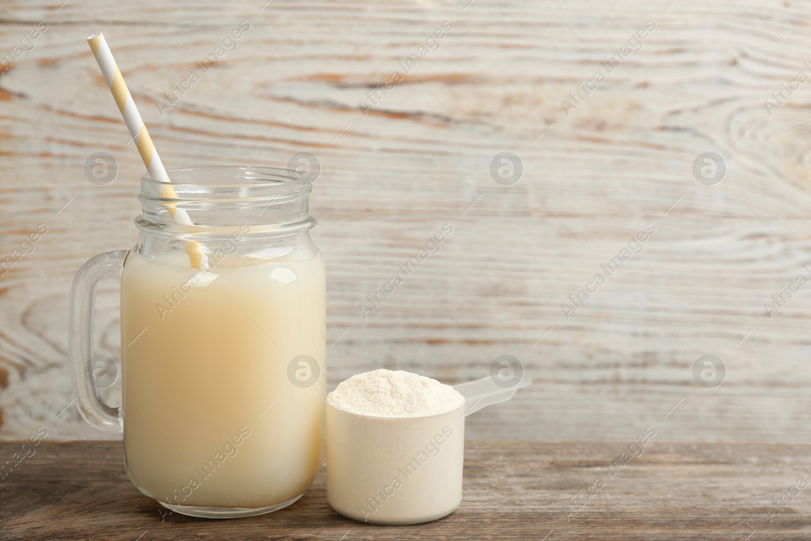 Photo of Protein shake and powder on wooden table, space for text