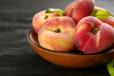 Photo of Fresh ripe donut peaches on black wooden table, closeup