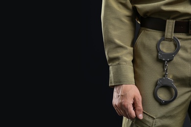 Photo of Male security guard with handcuffs on dark background, closeup