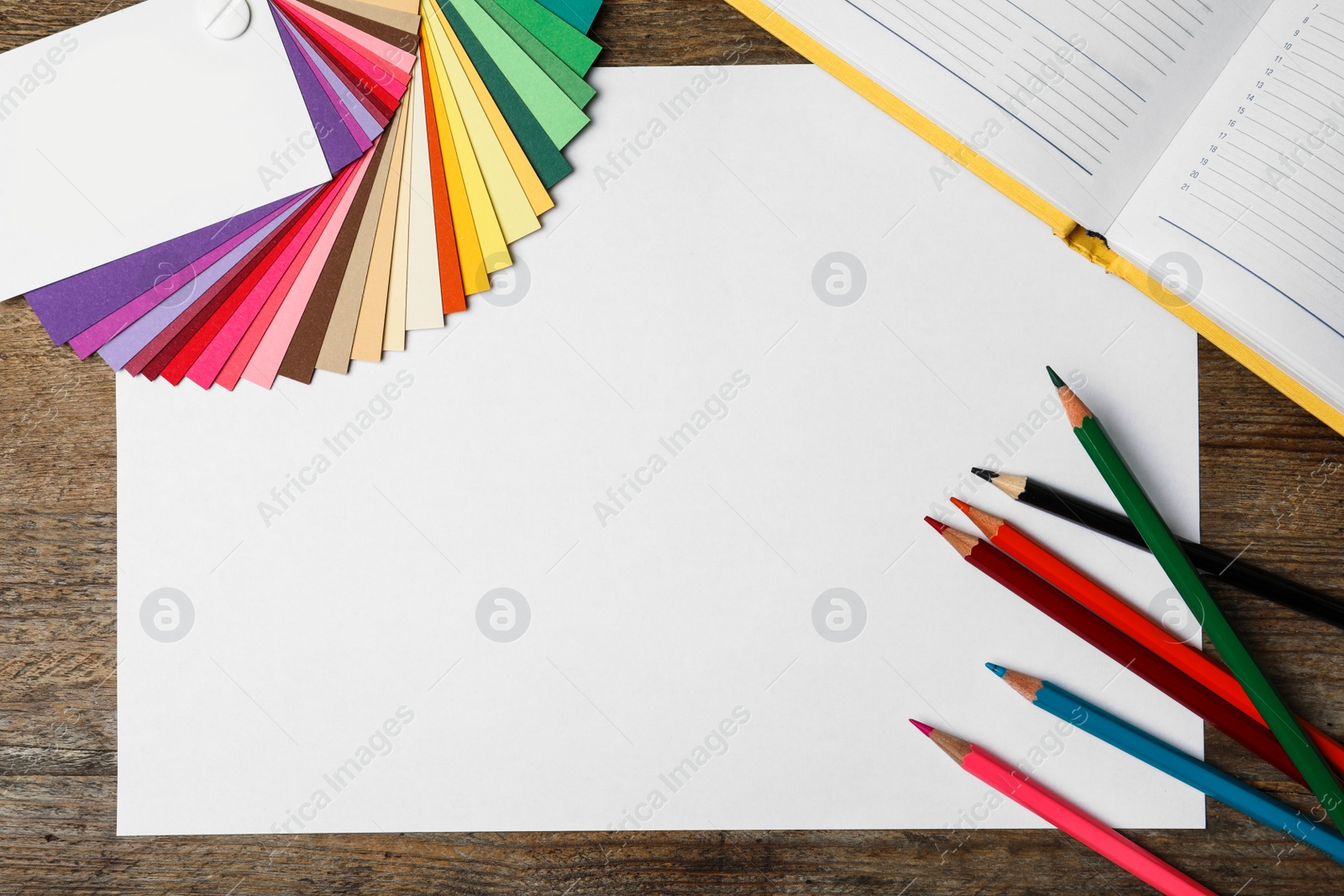 Photo of Color palette, notebook, pencils and blank paper sheet on wooden background, flat lay. Space for text