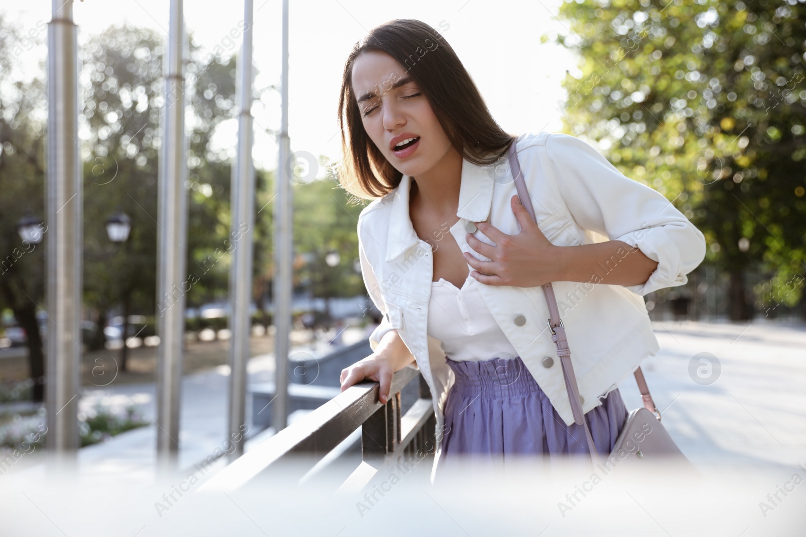 Photo of Young woman having heart attack on city street