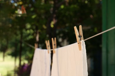 Washing line with clean laundry and clothespins outdoors, closeup