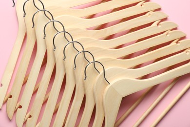 Many wooden hangers on pink background, top view