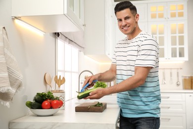Photo of Man peeling cucumber at kitchen counter. Preparing vegetable