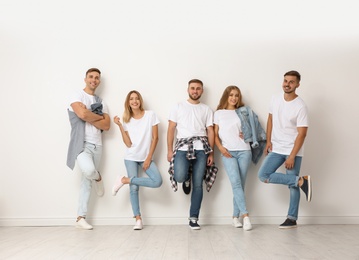 Photo of Group of young people in jeans near light wall