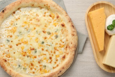 Delicious cheese pizza and different kinds of cheese on wooden table, flat lay