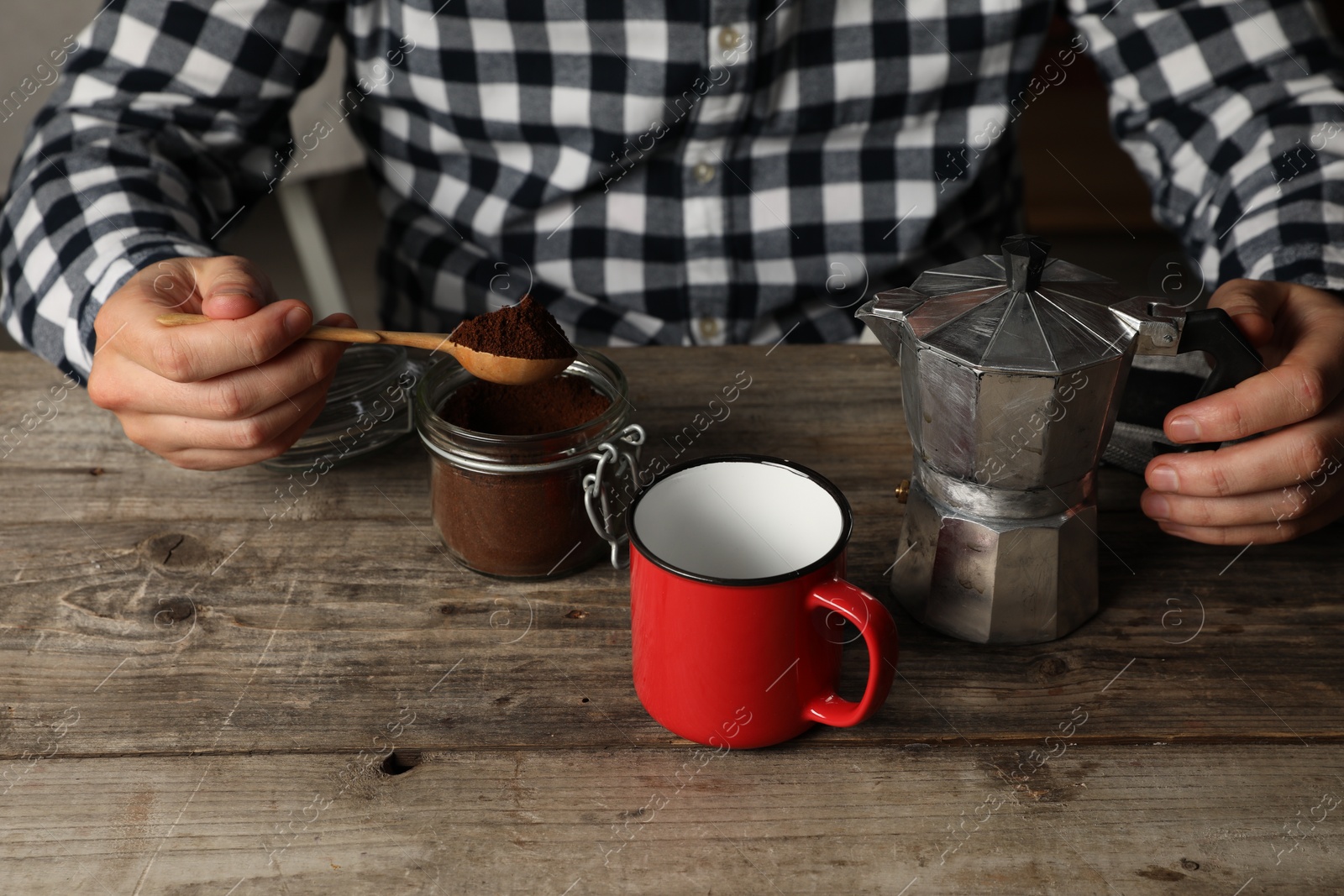 Photo of Man with moka pot and ground coffee at wooden table, closeup