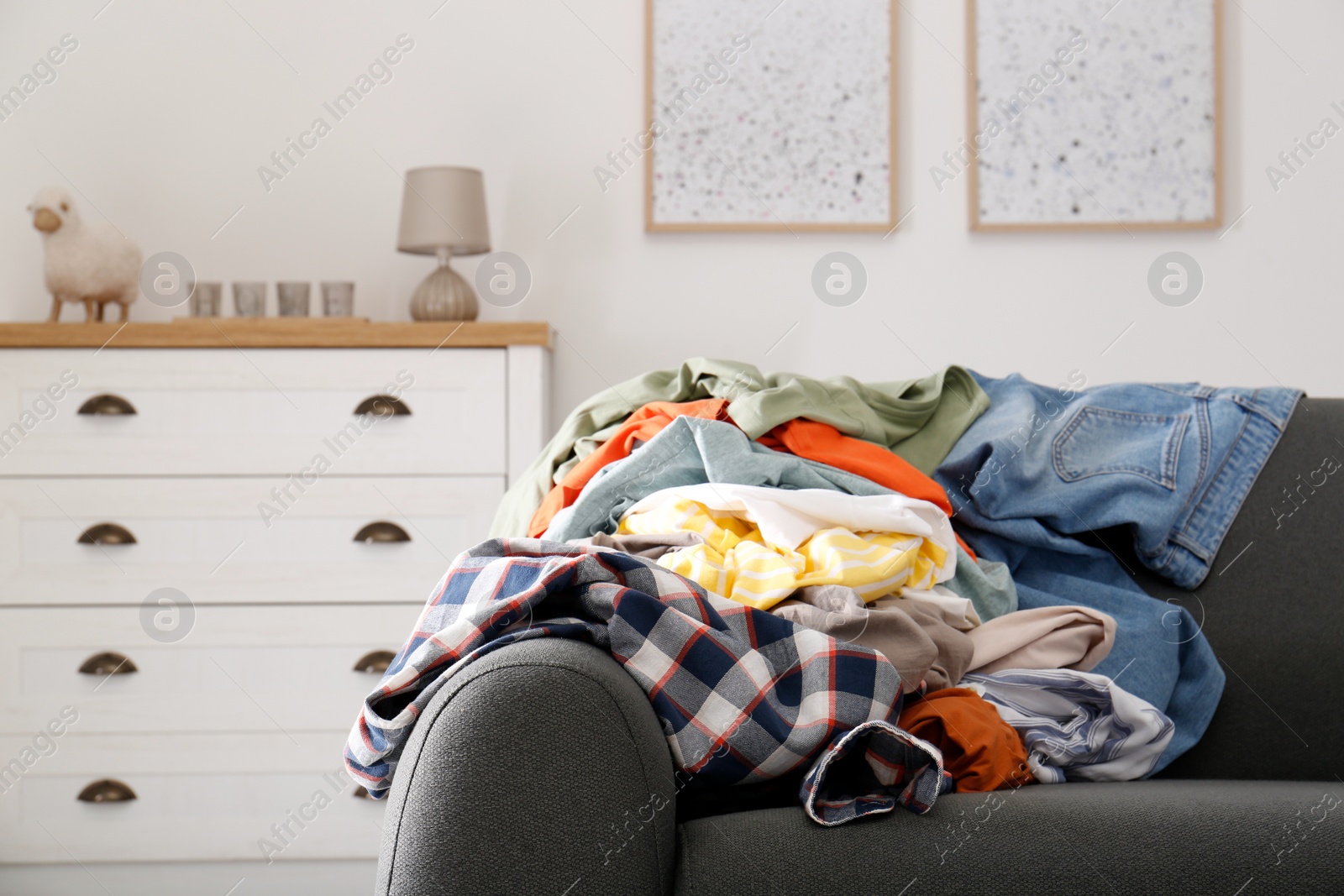 Photo of Messy pile of dirty clothes on sofa in living room. Tidying up method