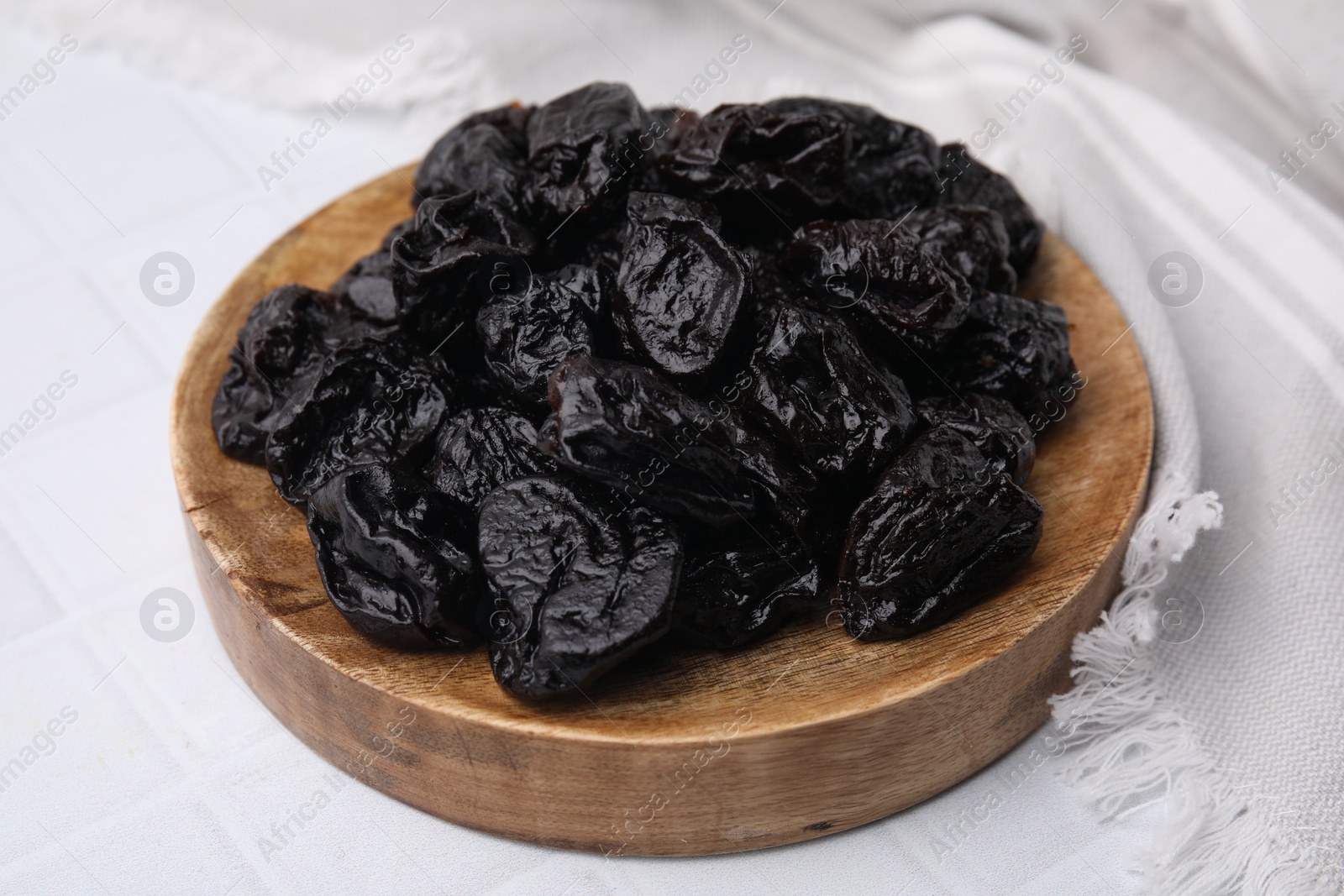 Photo of Sweet dried prunes on white tiled table, closeup