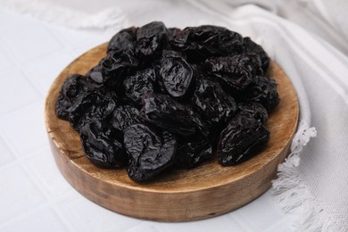 Sweet dried prunes on white tiled table, closeup