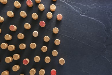 Photo of Wine bottle corks on black table, flat lay. Space for text