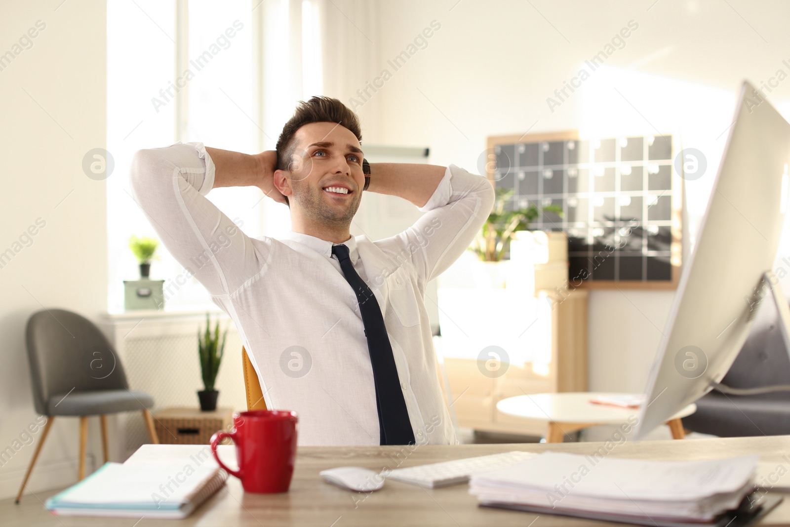 Photo of Young businessman relaxing at table in office during break