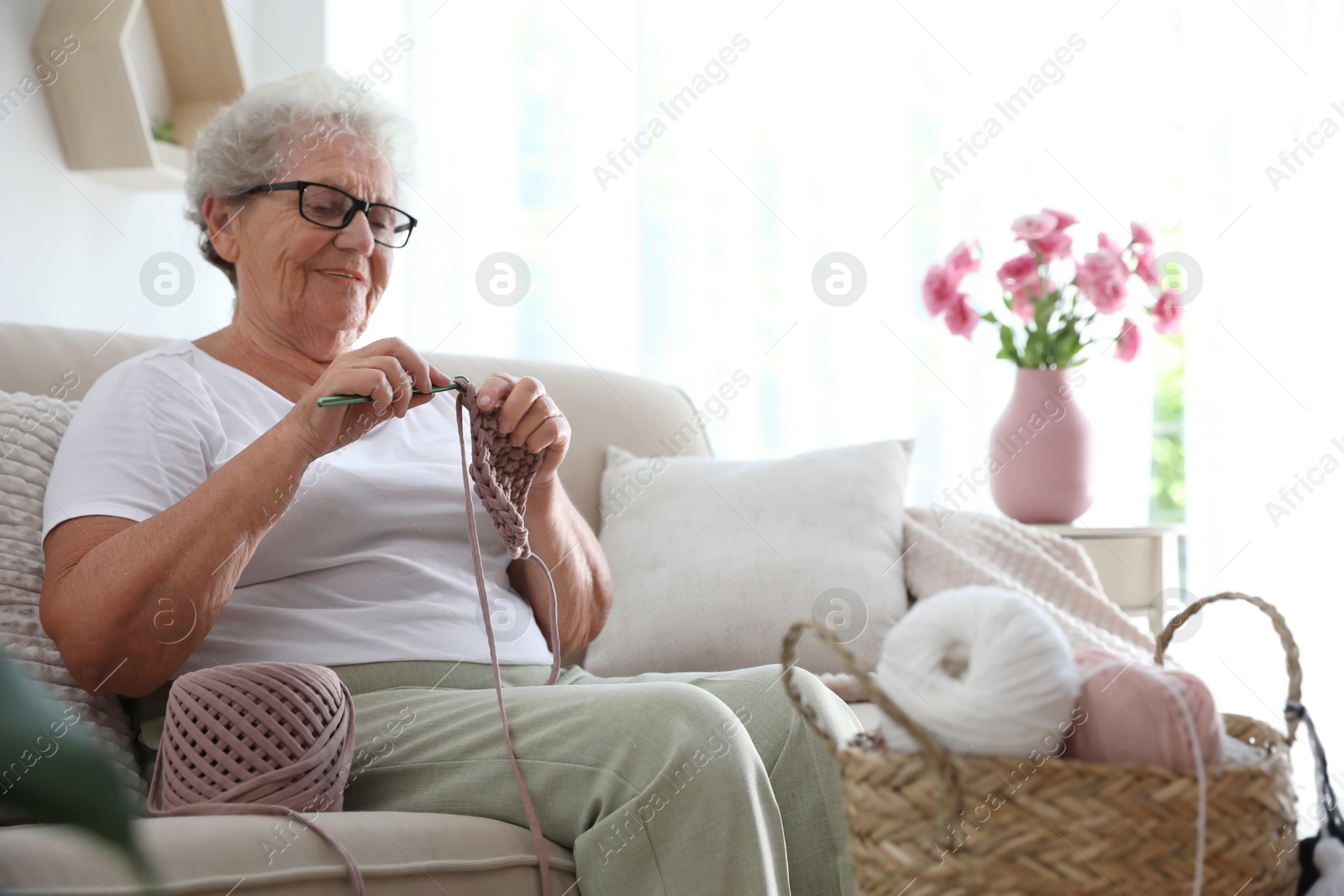 Photo of Elderly woman crocheting at home. Creative hobby