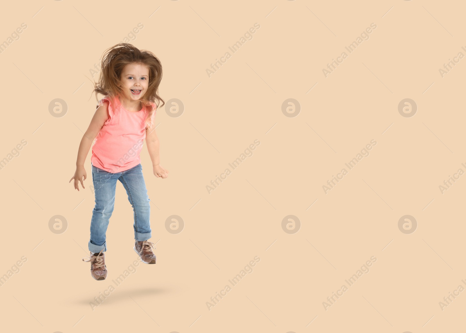 Image of Cute girl jumping on beige background, space for text