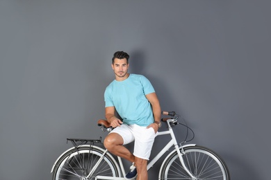 Photo of Handsome young hipster man with bicycle on color background