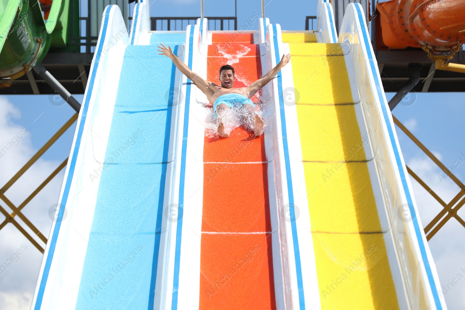 Photo of Man on slide at water park. Summer vacation