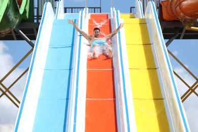 Photo of Man on slide at water park. Summer vacation