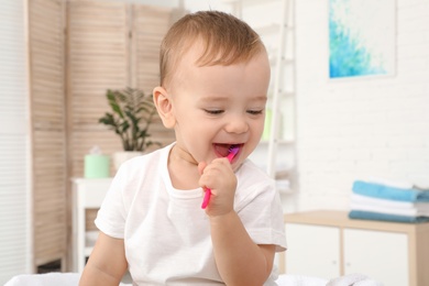 Photo of Cute little boy with toothbrush on blurred background