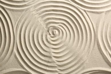Photo of Beautiful spirals on sand, top view. Zen garden