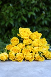 Beautiful bouquet of yellow roses on light table outdoors, space for text