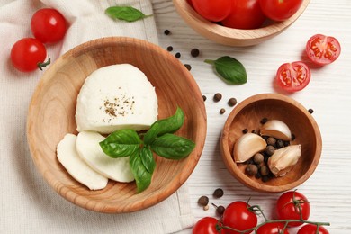 Delicious mozzarella with tomatoes and basil leaves on white wooden table, flat lay
