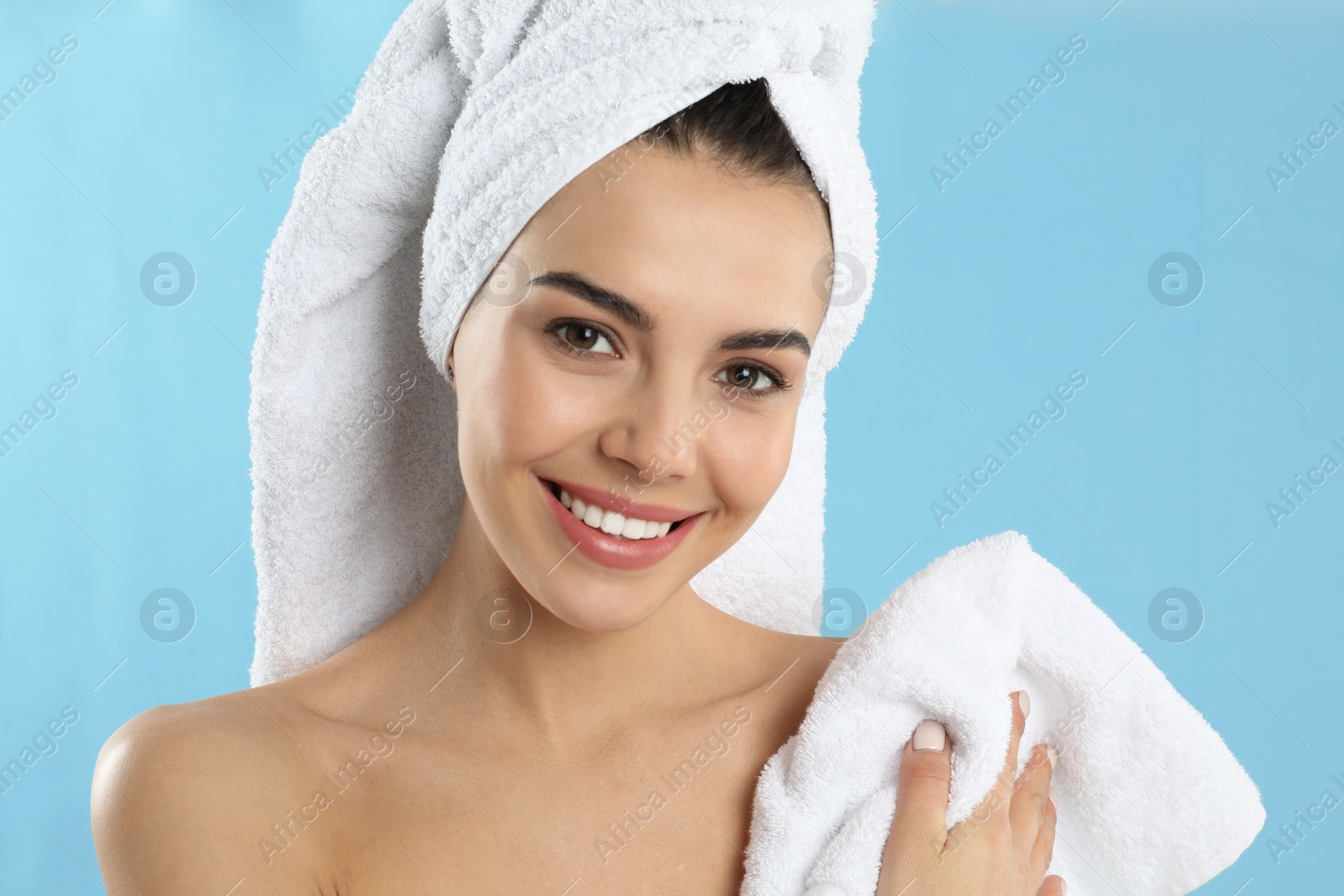 Photo of Young woman wiping body with towel on light blue background