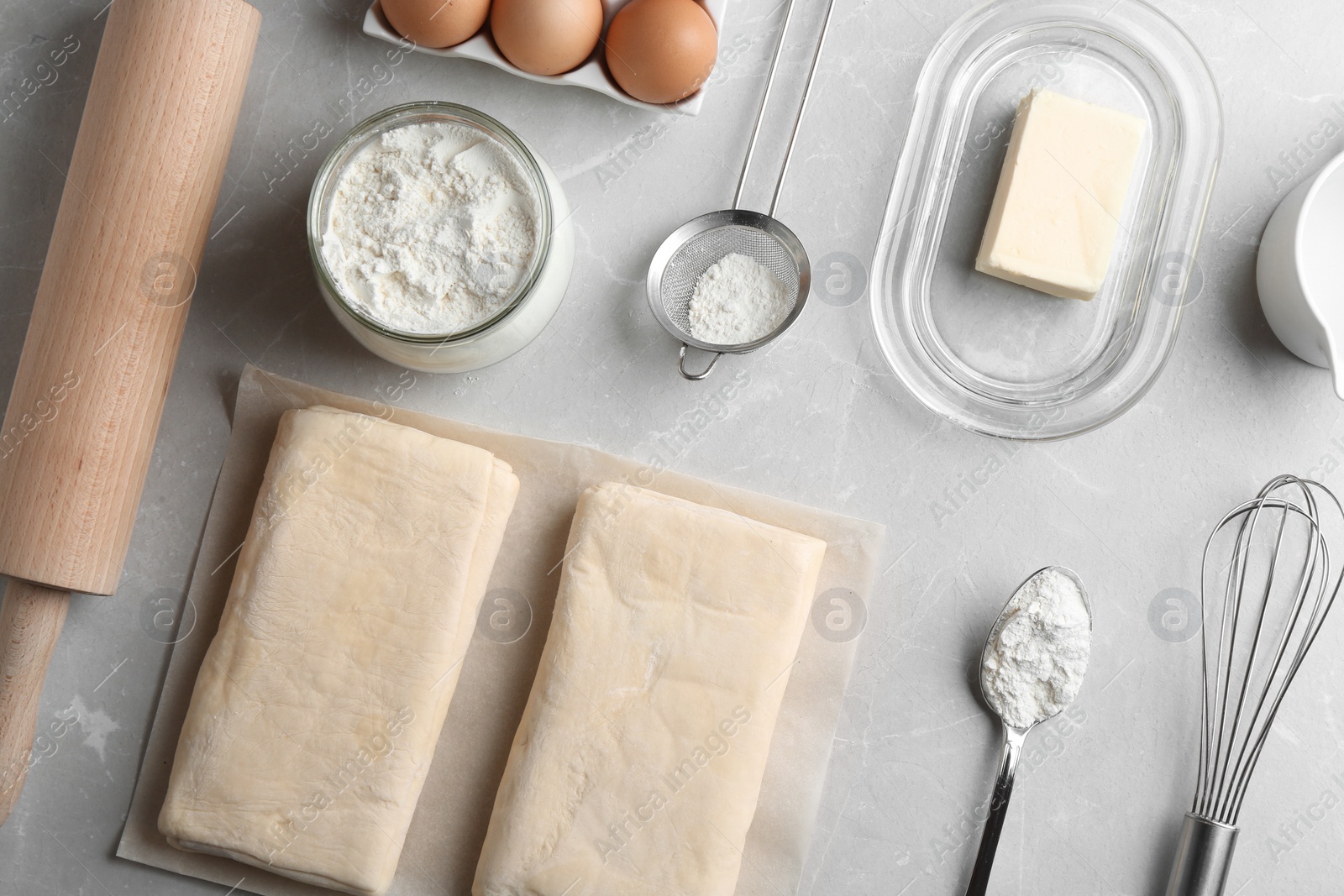 Photo of Flat lay composition with puff pastry dough and ingredients on grey table