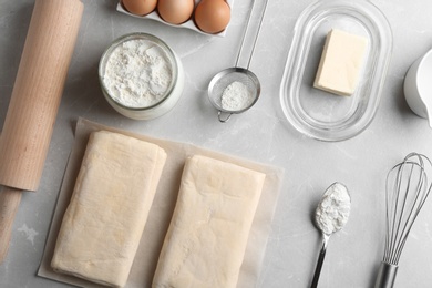 Flat lay composition with puff pastry dough and ingredients on grey table