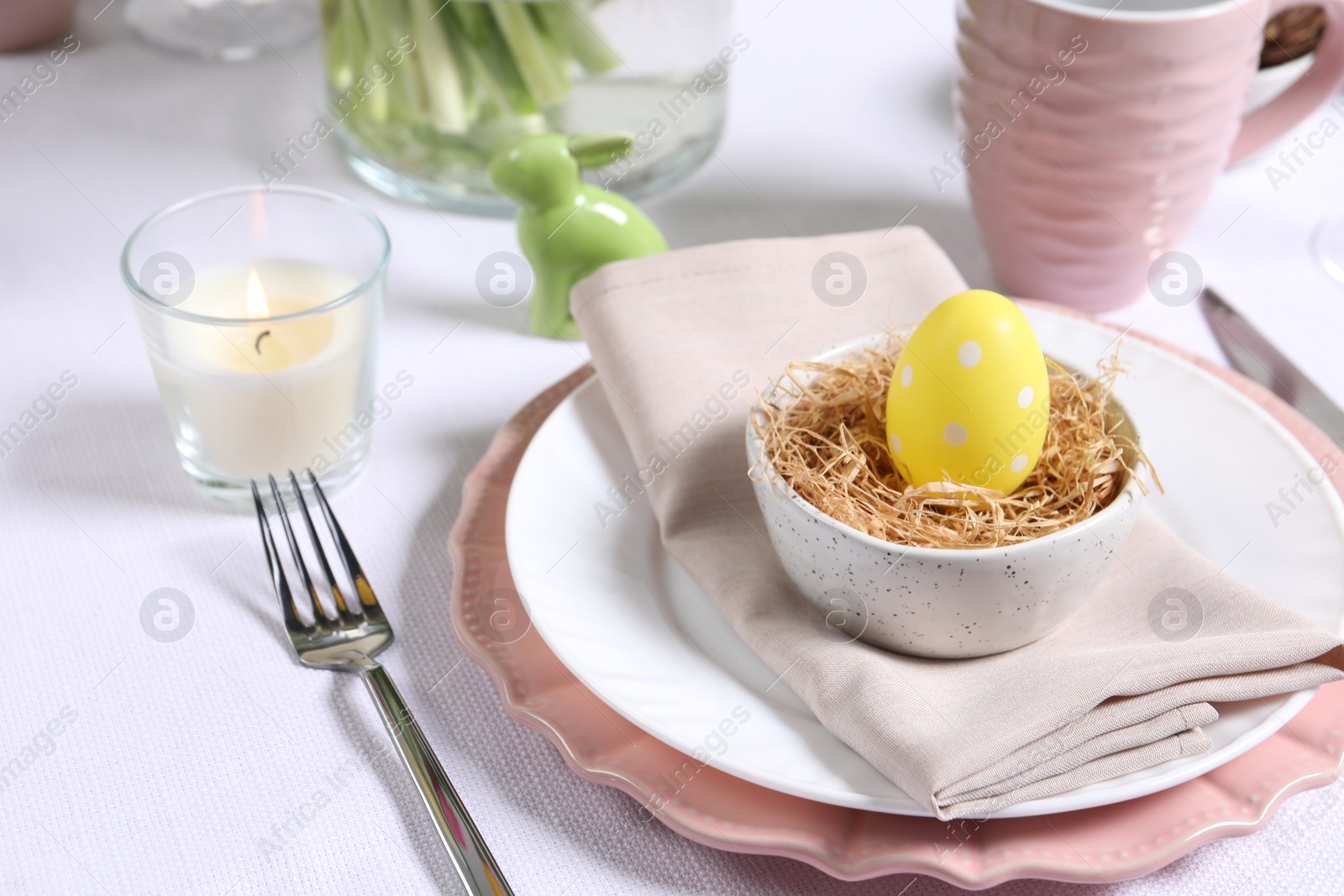 Photo of Festive table setting with painted egg in decorative nest. Easter celebration