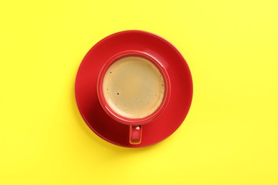 Photo of Tasty coffee in cup on yellow background, top view